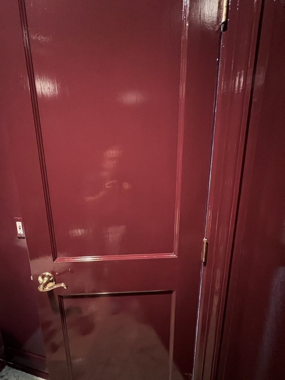 High-gloss oxblood door with brass lever hardware