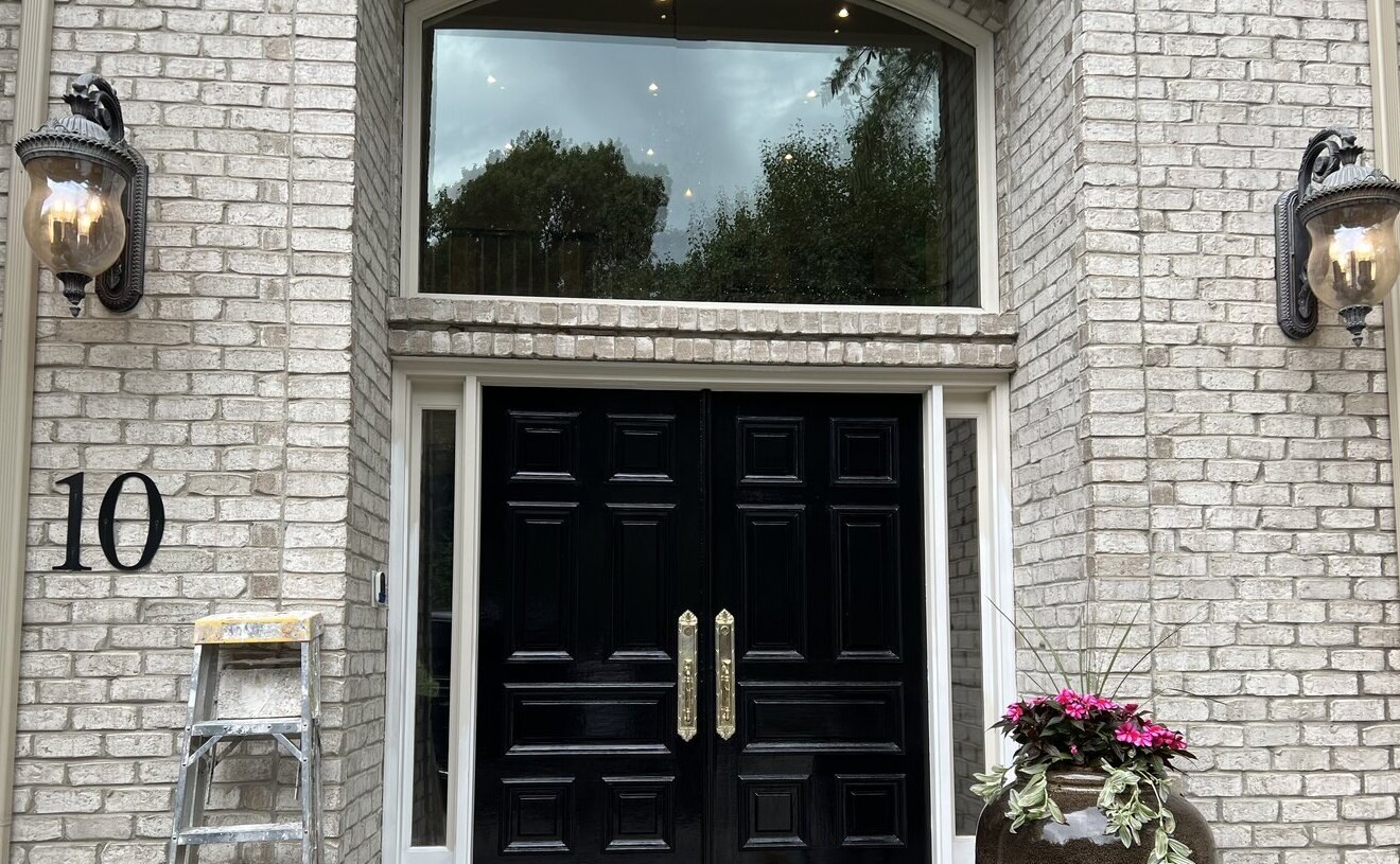 High-gloss black front doors on a brick home