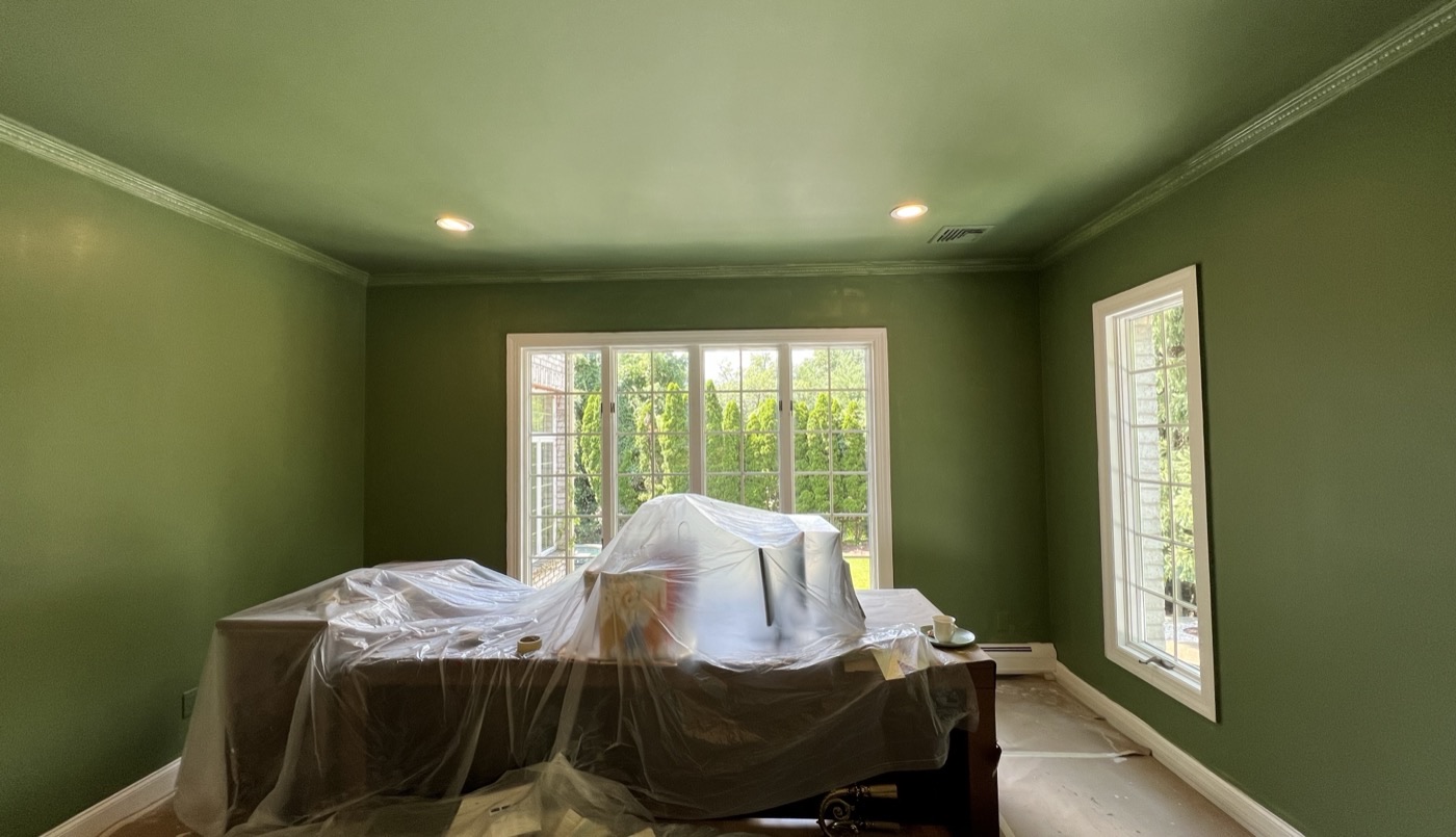 Bedroom painted deep green with white crown molding and window trim